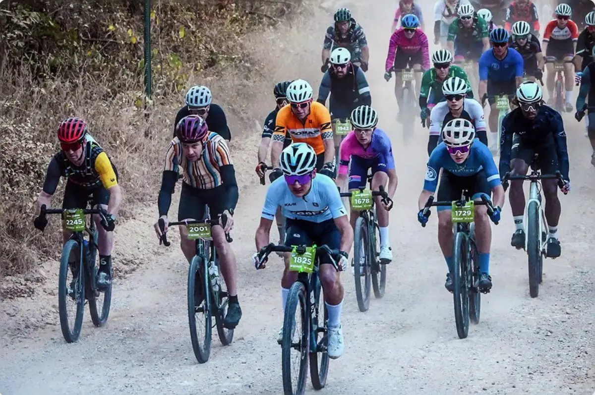 Pack of riders climbing a dusty gravel road during a mass-start cycling race in Arkansas