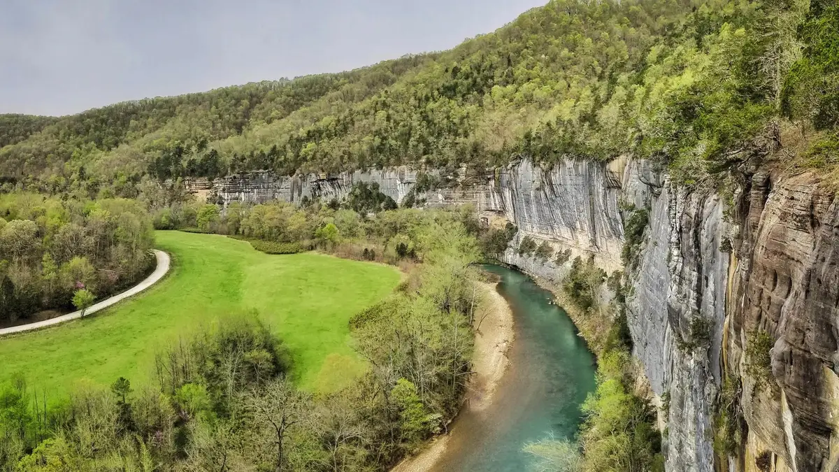 Limestone bluffs above a clear green river winding through the Ozark Mountains in Arkansas in spring