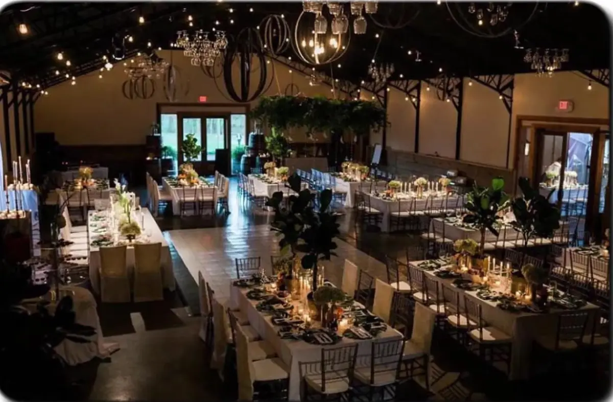 Candlelit banquet tables set under string lights and chandeliers in a vineyard event barn in Springdale, Arkansas