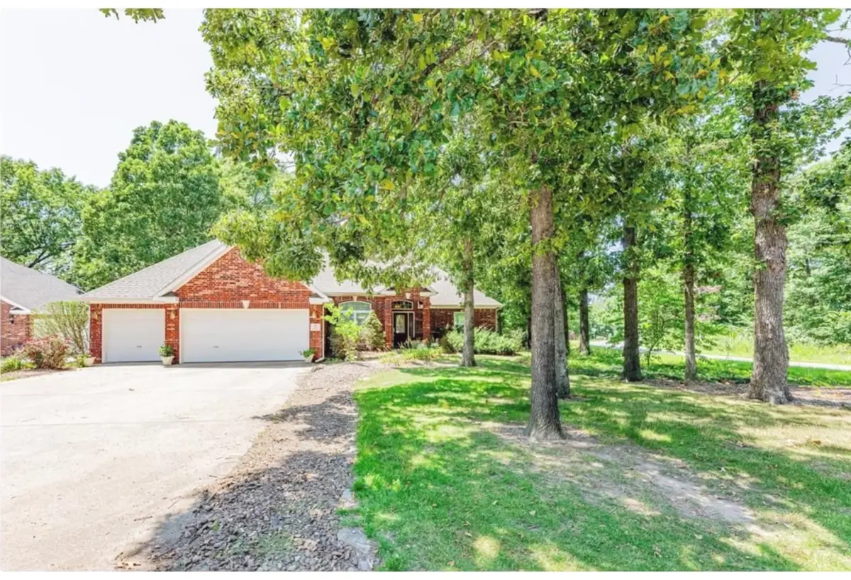 Brick ranch home with a two-car garage on a shaded, heavily wooded lot in Bella Vista, Arkansas
