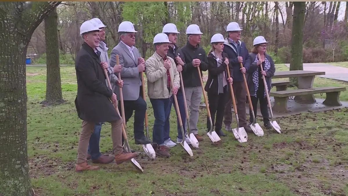 Officials in white hard hats holding ceremonial shovels at a housing development groundbreaking in Northwest Arkansas