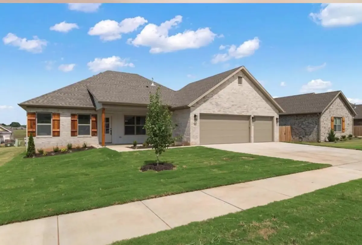 Newly built brick single-family home with a three-car garage in a Northwest Arkansas neighborhood