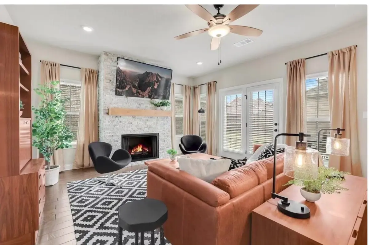 Furnished living room with a leather sofa, stone fireplace and natural light in a Northwest Arkansas rental home