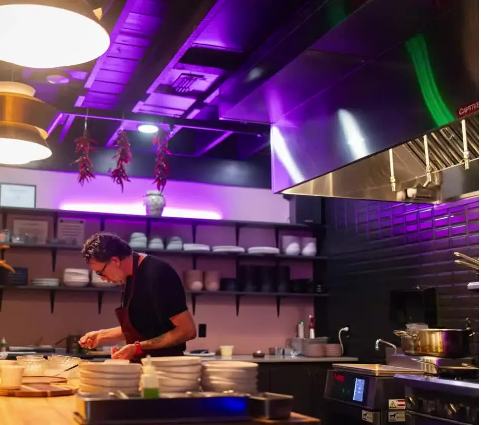 Chef plating a course at the open kitchen counter of Heirloom at the 1907, the fine dining restaurant in downtown Rogers, Arkansas