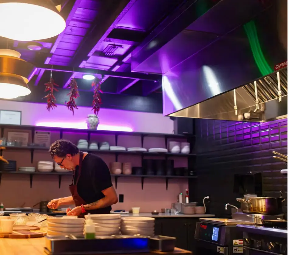 Chef plating a course at the open kitchen counter of Heirloom at the 1907, the fine dining restaurant in downtown Rogers, Arkansas