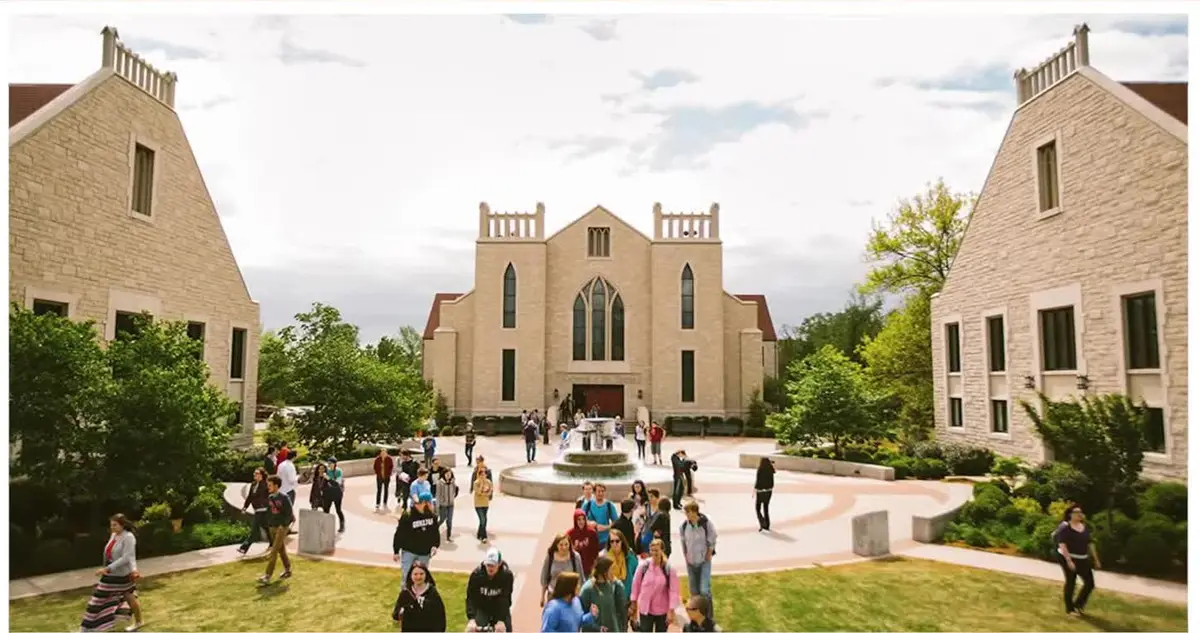 Students crossing the fountain plaza at John Brown University in Siloam Springs, Arkansas, with the campus chapel behind