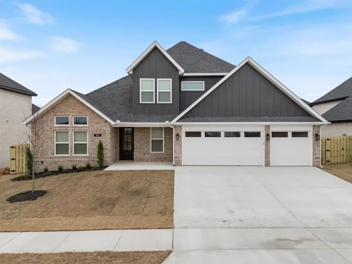 Newly built brick and board-and-batten home with a three-car garage in a new construction subdivision in Bentonville, Arkansas