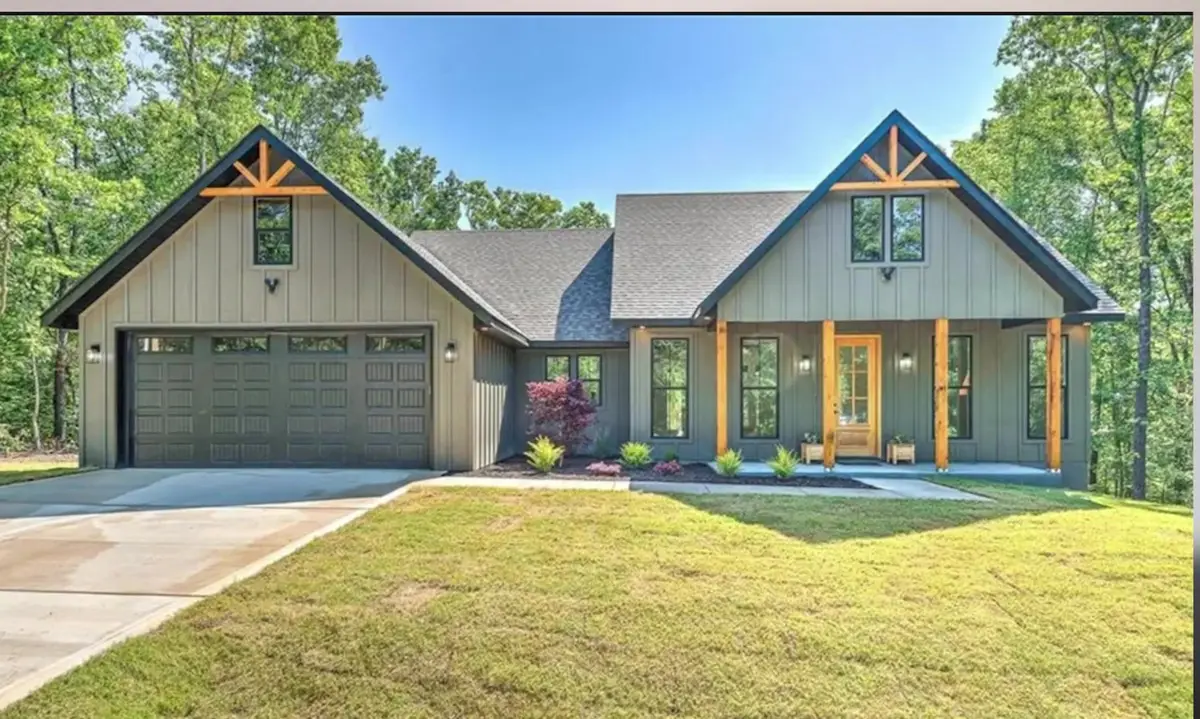 Newly built sage-green craftsman home with cedar accents on a wooded lot in Northwest Arkansas