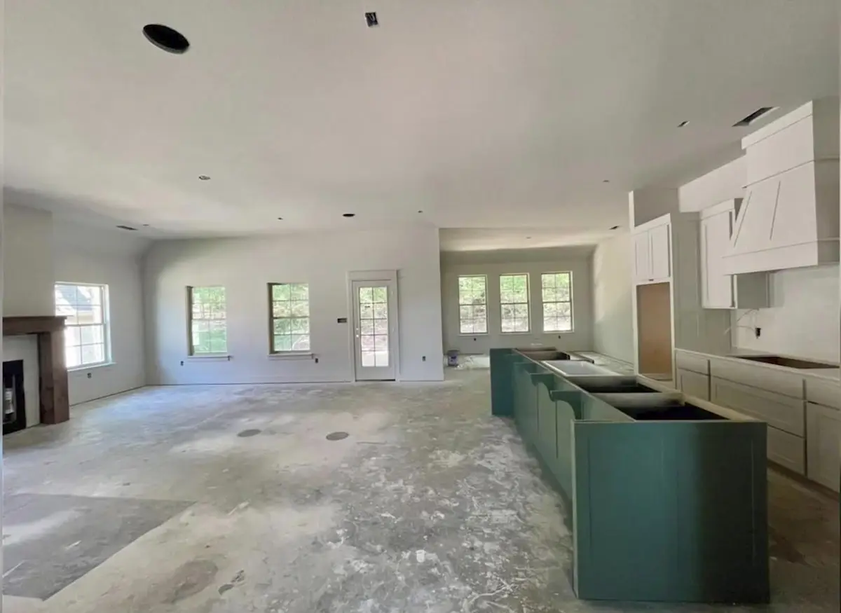Interior of a Northwest Arkansas home under construction, with a green kitchen island, unfinished concrete floor and new cabinetry