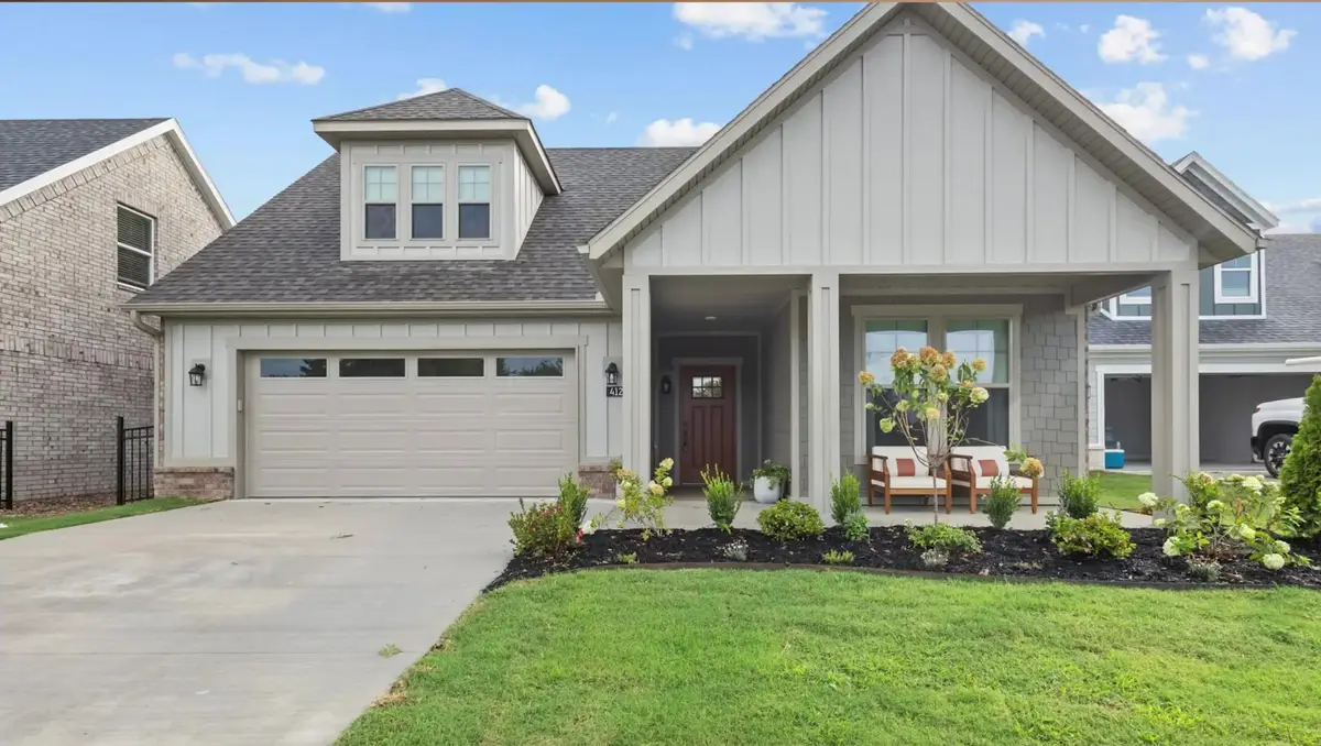 Newly built board-and-batten home with a two-car garage and covered porch in a Northwest Arkansas subdivision