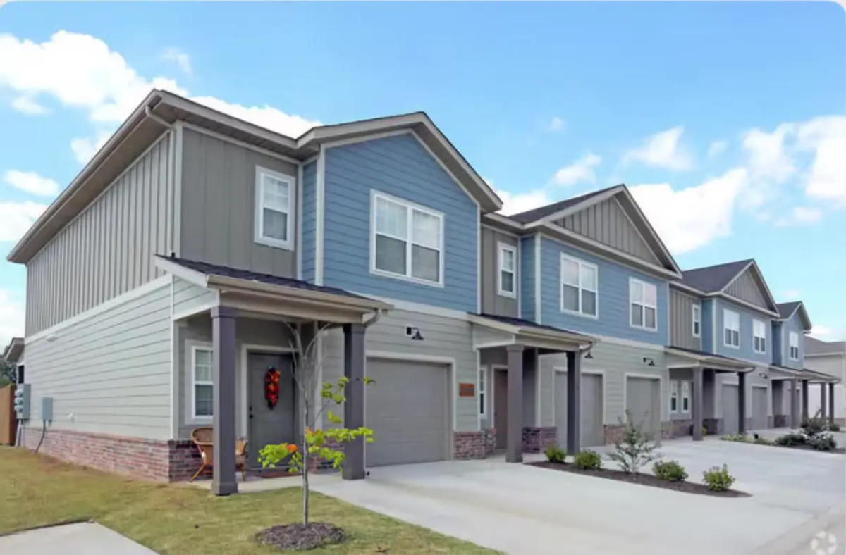 Row of newly built blue and grey townhomes with attached garages in a Northwest Arkansas neighborhood