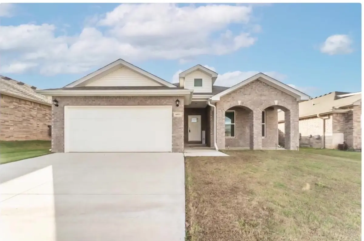 Single-story brick starter home with a two-car garage in a Northwest Arkansas subdivision