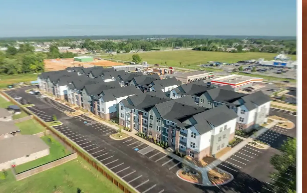 Aerial view of a newly built apartment complex in Pea Ridge, Arkansas, with retail and open farmland beyond it