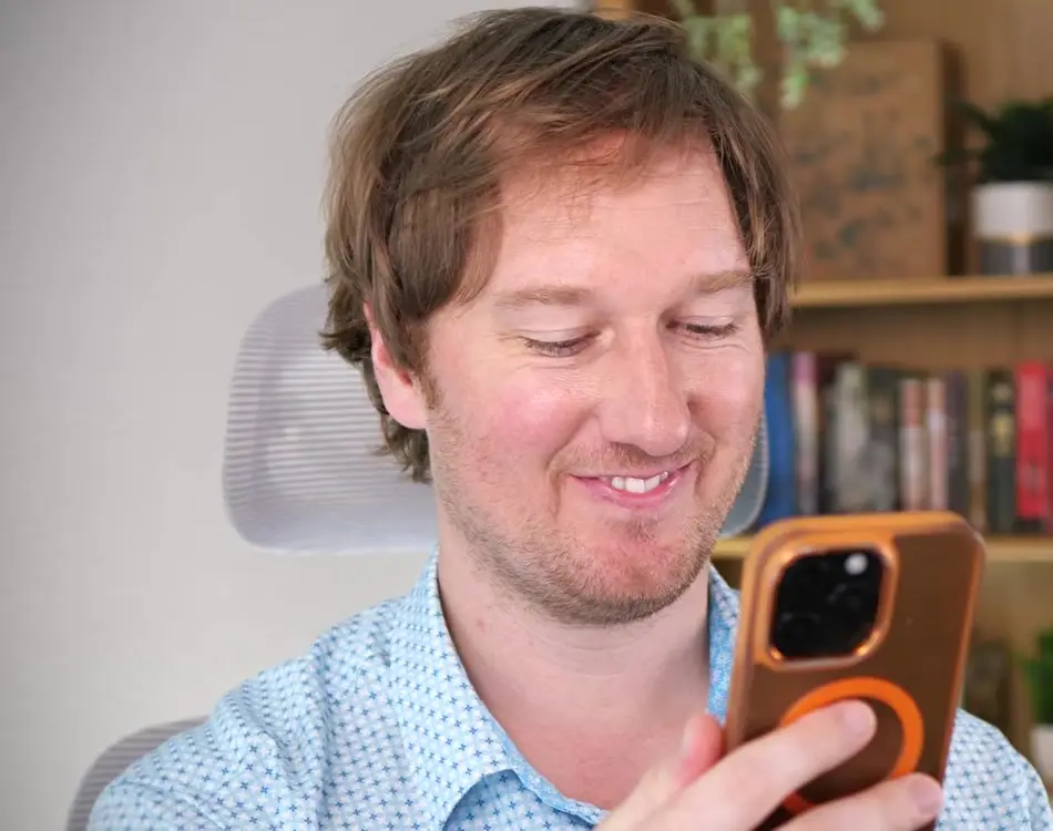 Phillip Shepard of All Things Northwest Arkansas smiling as he watches TikTok videos about the region on his phone