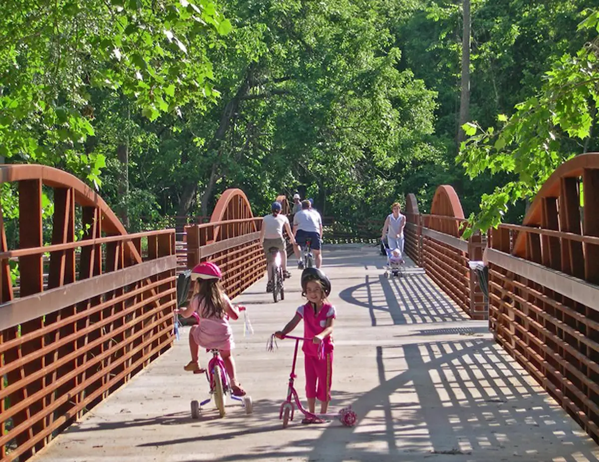 Families walking across an arched bridge on the Razorback Greenway in Northwest Arkansas