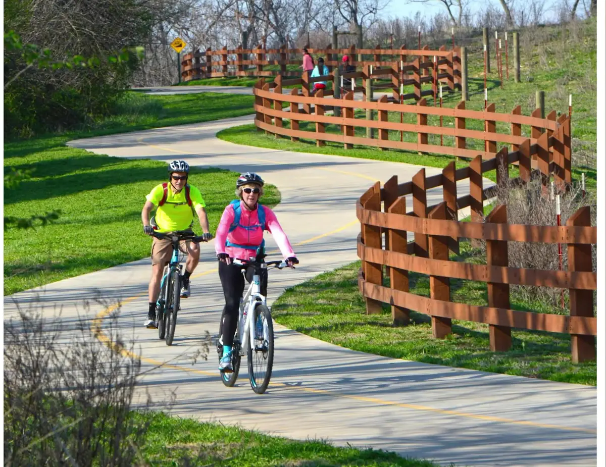 Two cyclists riding the paved Razorback Greenway trail in Northwest Arkansas