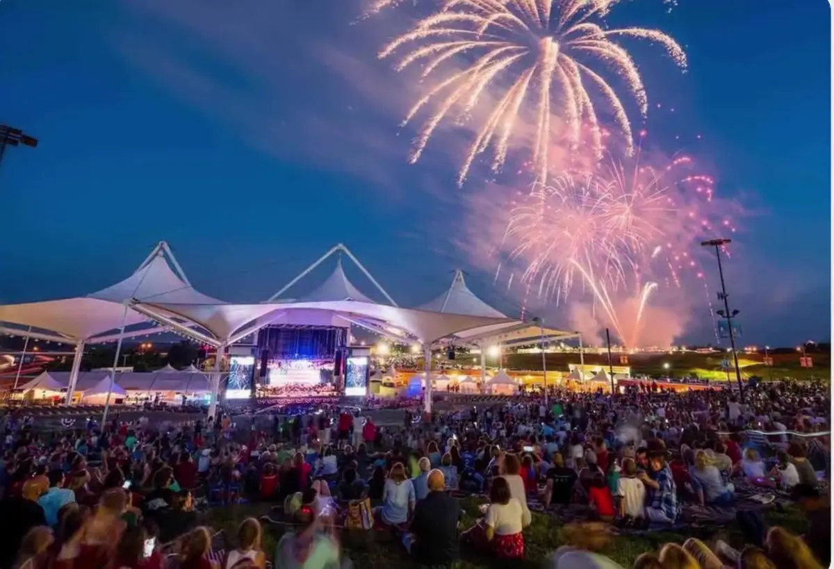 Fireworks over a packed lawn crowd at an outdoor amphitheatre concert in Rogers, Arkansas