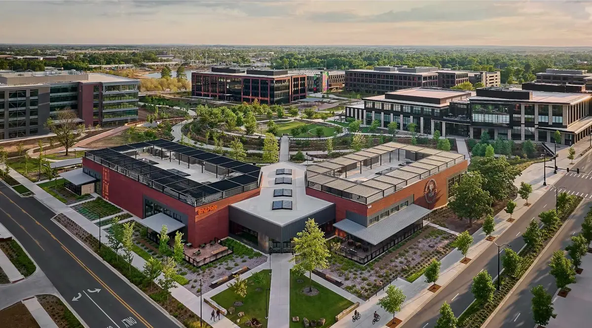 Aerial view of Walmart's home office campus in Bentonville, Arkansas, showing the 8th and Plate food hall, office buildings and landscaped walkways at sunset